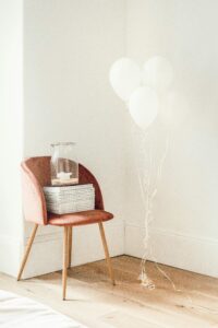 Cute corner of a new home, with a chair, small decors and white balloons on the side.